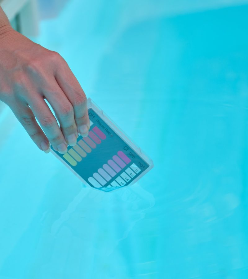 Woman hand filling ph and cl kit with pool water to test the quality.